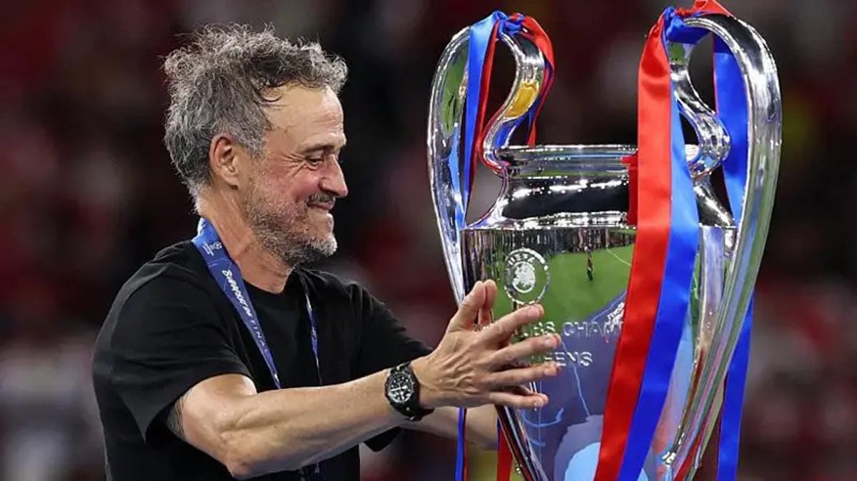 Paris Saint-Germain manager Luis Enrique smiling and celebrating with the Champions League trophy.