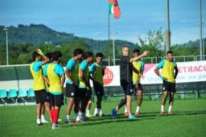 Head coach Thomas Dooley explaining tactics to captain Jamal Bhuyan and others on the pitch.
