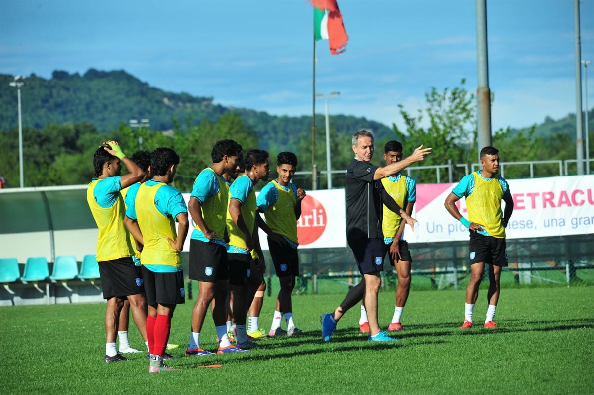 Head coach Thomas Dooley explaining tactics to captain Jamal Bhuyan and others on the pitch.